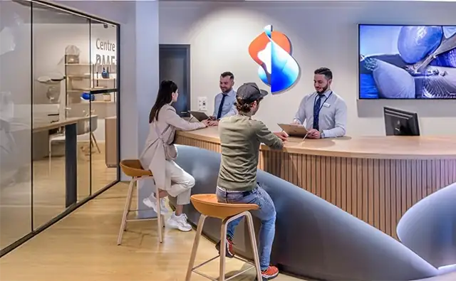 Modernes Swisscom Kundencenter in dem zwei Kunden an einer Theke sitzen und von Kundenberatern individuell betreut werden.