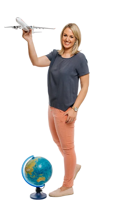 Mag. Katrin Groiss-Schuster hält ein Modellflugzeug in der einen Hand, mit einem Globus zu ihren Füssen - voller Fernweh und Reiselust.