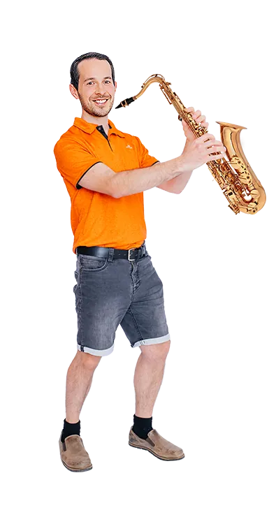 Andreas Kritsch steht mit einem Saxophon in den Händen und lächelt in die Kamera - musikalisch, humorvoll und voller Spielfreude.