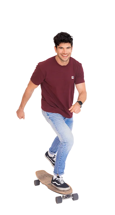 Christoph Halbertschlager fährt schwungvoll auf einem Longboard, lächelt und trägt sportlich-leger Jeans und Shirt - voller Dynamik und Spass an Bewegung.