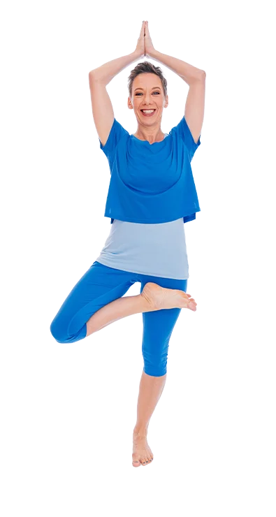 Dagmar Jiresch steht barfuss in der Baumposition und trägt ein blaues Yoga-Outfit - voller Balance, Energie und innerer Ruhe.