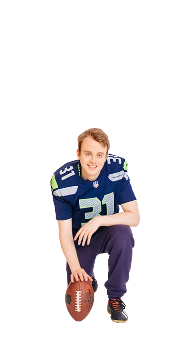 Jan-Michael Bussmann kniet im American-Football-Outfit mit einem Football in der Hand - sportlich, entschlossen und bereit für den nächsten Spielzug.