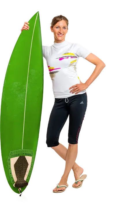Martina Bauer, PhD lehnt entspannt an einem grossen, grünen Surfbrett, trägt Sportkleidung und Flip-Flops - bereit für die nächste Welle am Strand.