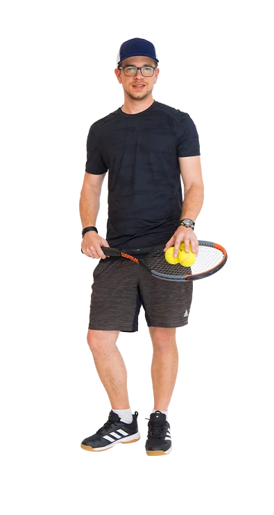 Matthias Kausel steht im Sportoutfit mit Tennisschläger in der Hand und zwei Tennisbällen - sportlich, fokussiert und bereit für das nächste Match.