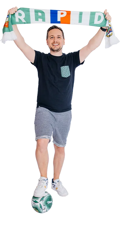 Matthias Obermeier jubelt mit einem Fussballschal und balanciert einen Ball am Fuss - sportlich, energiegeladen und voller Teamgeist.
