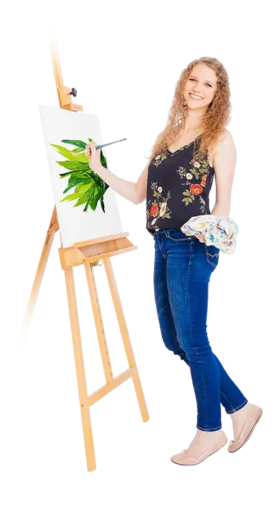 Sophie Buchta steht vor einer Staffelei und malt grüne Pflanzen auf eine Leinwand, das Tuch in der Hand - naturverbunden, fröhlich und voller Kreativität.